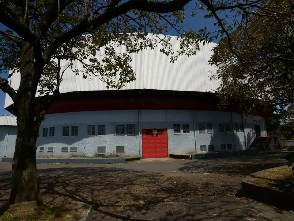 Entrada del Gimnasio Nacional con su puerta roja entre los árboles